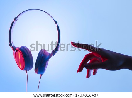 Female hand and headphones in neon, free space