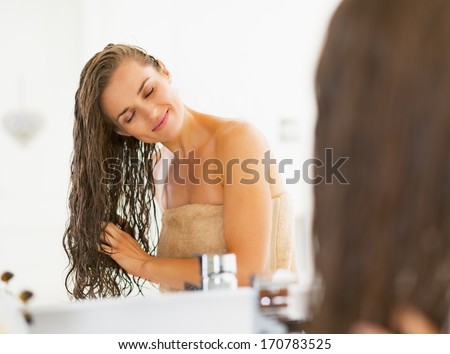 Happy young woman with wet hair in bathroom Royalty-Free Stock Photo #170783525