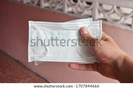 hand with a medical face mask for protection against infection