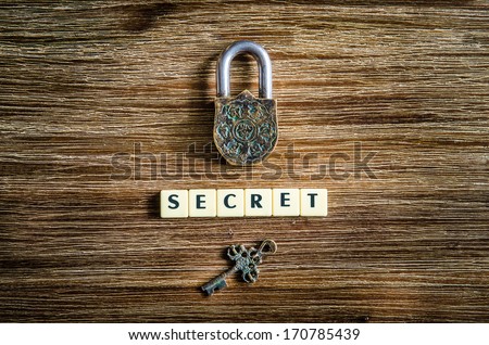 Old vintage padlock and key on wooden texture with secret sign