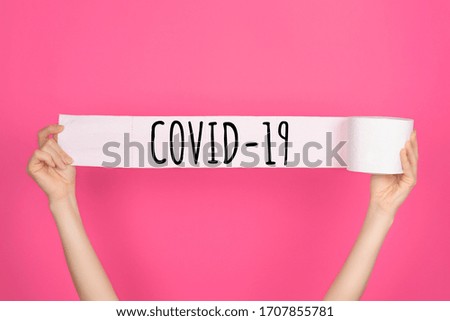 Soft, white toilet paper roll on bright pink background. Hygiene concept. Copy space for text, object or logo. Covid 19 lettering on white toilet paper.