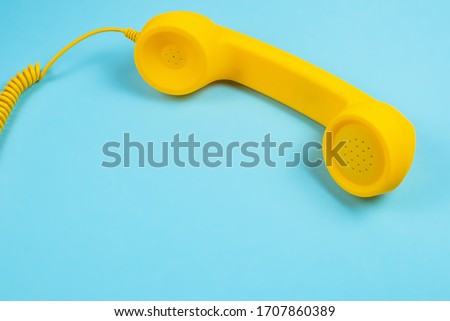 Yellow handset on a blue background. Copy space.