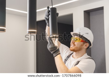 Electrician installs lamp lighting and spot loft style on ceiling. Royalty-Free Stock Photo #1707866098