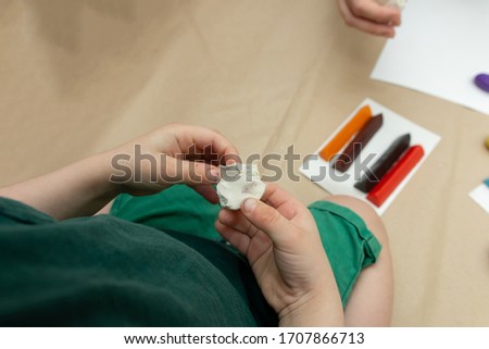a small child kneads a white piece of plasticine. children's crafts to school, kindergarten.