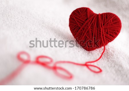 Red heart shape symbol made from wool isolated on textured white background