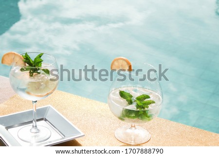 Picture in the pool with refreshing drinks or cocktails with lemon on summer vacation