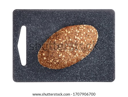 Isolated bread with seeds and flakes on grey rectangular cutting board on white background top view.