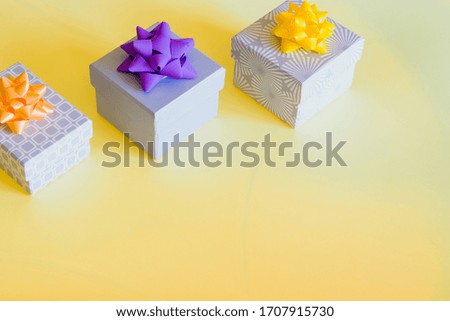 Colorful gift boxes and bows on sunny yellow background. Festive happy holidays design. 