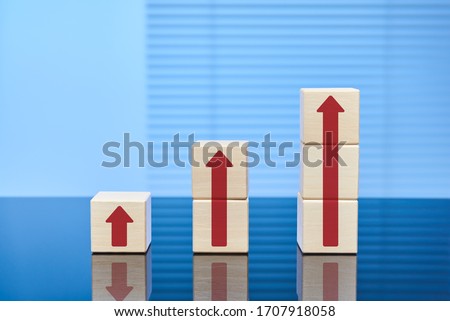 Visual business concept of the growth process. Wooden cubes on a blue background in ascending order with arrows going up. The concept of growth, revenue or price increase.