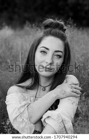 Alex crosses one arm over her chest as she faces the camera during a portrait in a meadow of long grass near Liverpool.