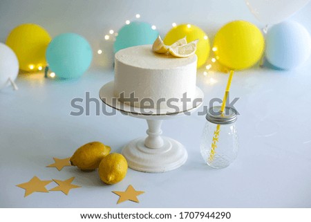 sponge cake on a white wooden stand, prepared for the celebration of the first year of the baby. photo zone with yellow and blue balloons