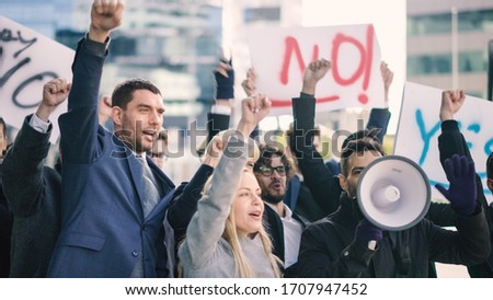 Multicultural Diverse Office Managers and Business People Picketing Outside on a Street. Men and Women Screaming for Justice, Holding a Megaphone, Picket Signs and Posters. Economic Crisis Strike. Royalty-Free Stock Photo #1707947452