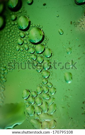 Green Glass Of A Bottle With Water Drops On Surface
