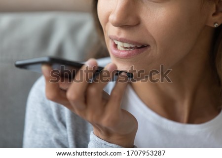 Close up woman recording voice message, speaking, young female holding phone in hand near face, chatting with friends online or speakerphone, activating digital assistant on smartphone