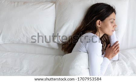 Top view close up unhappy woman lying on one half of empty bed alone, feeling lonely after quarrel with boyfriend, break up or divorce, upset young female suffering from bad dreams or insomnia Royalty-Free Stock Photo #1707953584