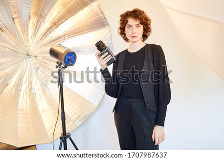 Young woman with medium format camera in front of a flash unit in the photo studio
