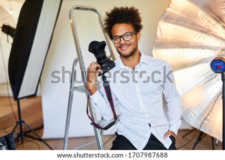 Successful young man as a photographer in the photo studio with camera