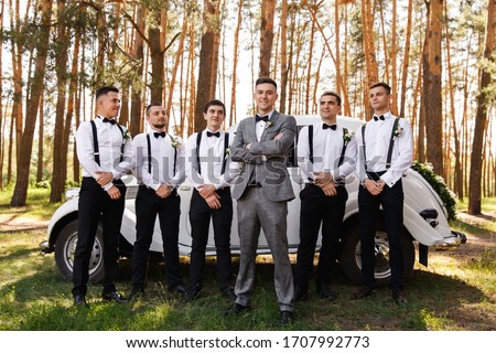 Group wedding photo of elegant groom in grey suit and groomsmen with black bow ties and suspender at wedding day Royalty-Free Stock Photo #1707992773