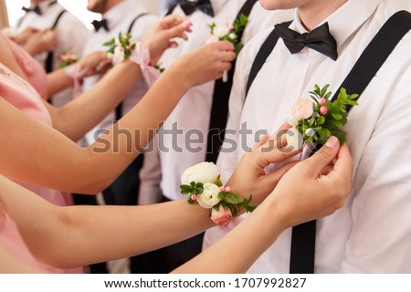 Bridesmaids put small bouquets on shirt of groomsmen at wedding day Royalty-Free Stock Photo #1707992827