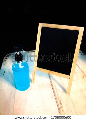 Hand sanitizer bottle and message board on a black background