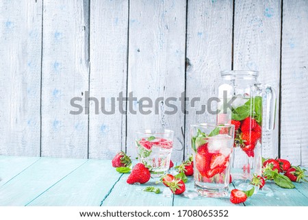 Strawberry and basil detox infused water. Summer diet healthy drink with strawberries and basil leaves. Wooden background copy space