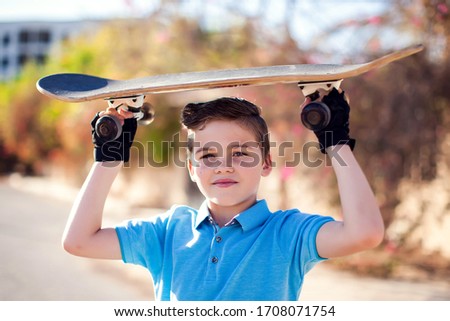 Kid boy with skateboard on the street. Childhood, leasure and lifestyle concept