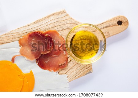 ham with olive oil, tomatoes and bread on a table and white background