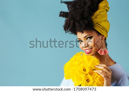 Portrait of a beautiful young woman  with green eye shadow make up smelling bouquet of fresh yellow daffodil flowers and looking at camera