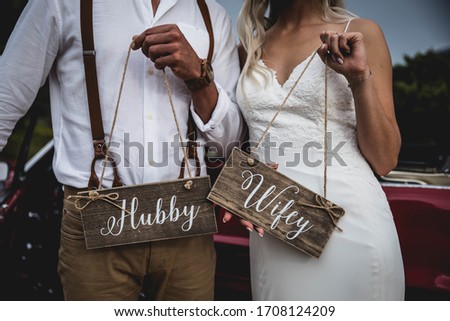 bride and groom close up holding hubby & wifey wooden printed signs on their wedding day Royalty-Free Stock Photo #1708124209