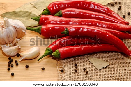 Composition of bay leaves, black paper with garlic and red chili pepper. wooden background top view
