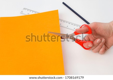 Scissors cut colored paper. hand with pencil and ruler