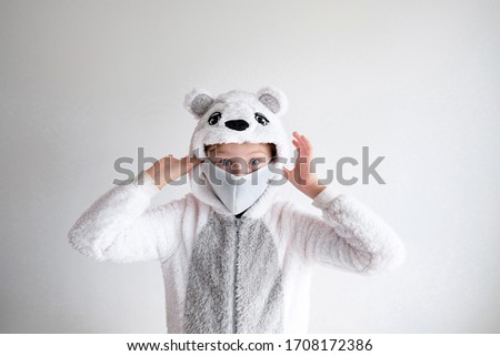 little girl in animal pajamas and protective face mask. a polar bear pajama is put on a child