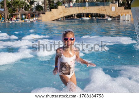 Girl in a bathing suit with sunglasses in the pool with foam