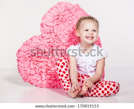 Valentine's Day. Beautiful small girl with a large red heart-shape indoor