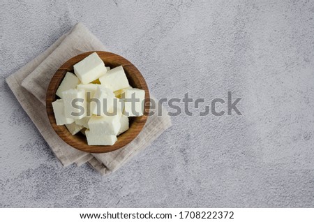 Homemade Indian paneer cheese made from fresh milk and lemon juice, diced in a wooden bowl on a gray stone background. Horizontal orientation. Top view. Copy space. Royalty-Free Stock Photo #1708222372