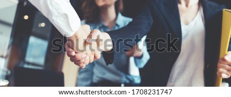 Young business people shaking hands in the office. Finishing successful meeting. Three persons. Wide screen panoramic Royalty-Free Stock Photo #1708231747