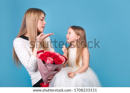 Little cute daughter and mother with bouquet of flowers on blue background