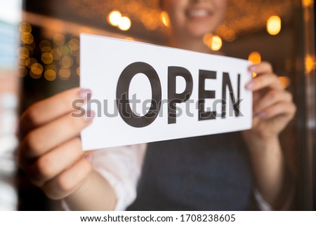 Hands of young waiter or owner of restaurant or cafe putting notice open on the door at the beginning of working day