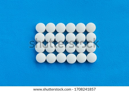 White tablets are laid out in the form of a rectangle on a blue background. There is space for text. Vitamins and nutritional supplements for health.