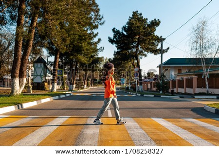 A young woman crosses a pedestrian crossing. Empty road and streets. Side view. Concept of traffic rules
