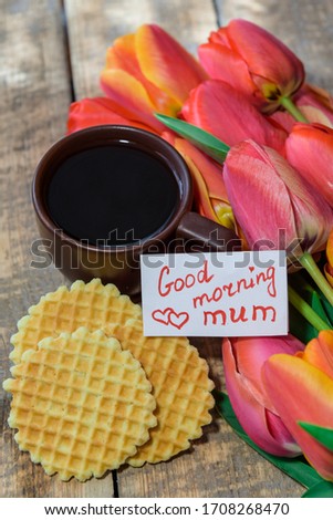 Breakfast. Coffee in bed. A cup of coffee with the note "Good morning mum" and tulips. Coffee and waffles for breakfast.