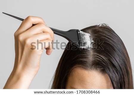 Closeup woman hands dyeing hair using a black brush. Colouring of white hair at home. Royalty-Free Stock Photo #1708308466