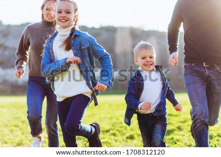 Happy family runs across the field. Father, mother and children run through a green field.