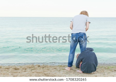 Mutual understanding between the parent and the child. Teenage daughter hugging mother's leg on the beach.