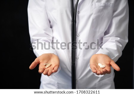 Cropped view of female Doctor holding in hands Pills to choose. Difficult Choice between drugs. Placebo drugs concept. Healthcare concept. Royalty-Free Stock Photo #1708322611