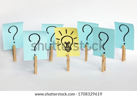 A lot of clothespins with question marks on stickers and on one light bulb, as a sign of a good idea. Concept of business, management, markets, creativity.