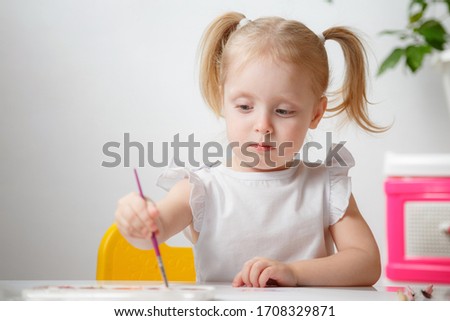 pretty kid girl painting with watercolours at home