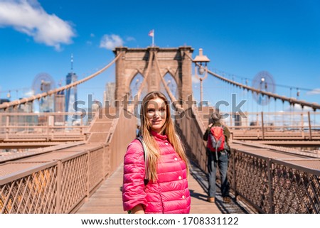 Young beautiful girl walking down the  Brooklyn Bridge with a magical Manhattan island view.