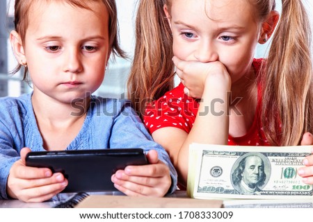 Close up business child girls with smart phone and US Dollar banknotes as symbol of online banking. Humorous picture.
