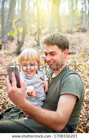 Dad and child make a video call online to family or friends and wave their hands at the camera.